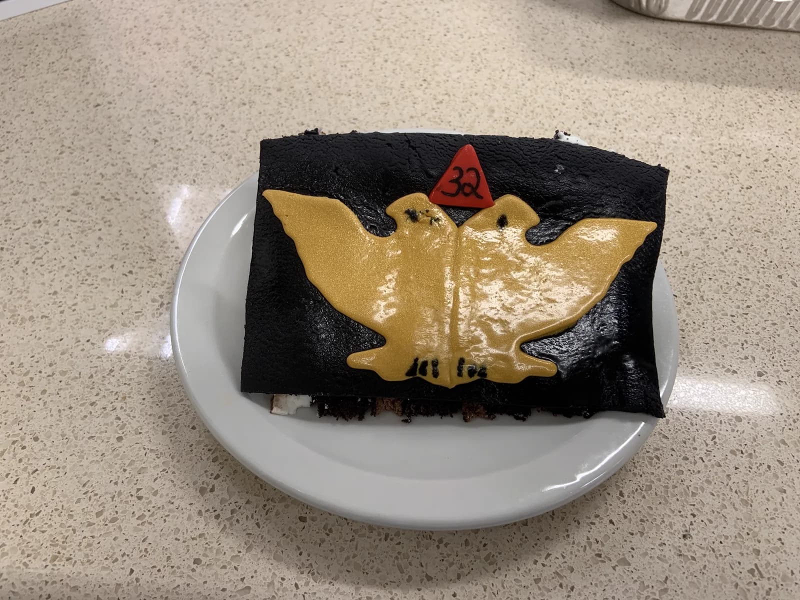 Close-up of a celebration cake decorated with a gold double-headed eagle and 32° emblem